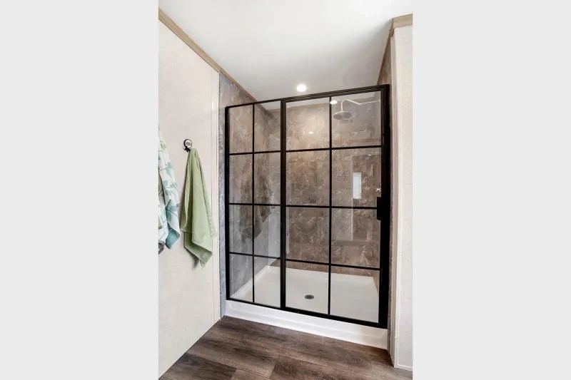 A bathroom with a walk in shower and a towel hanging on the wall.