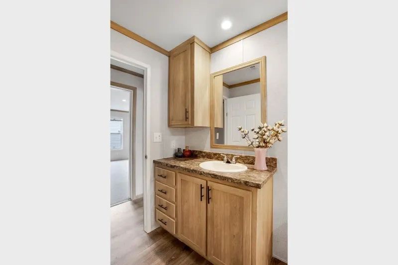 A bathroom with a sink , mirror and cabinets.