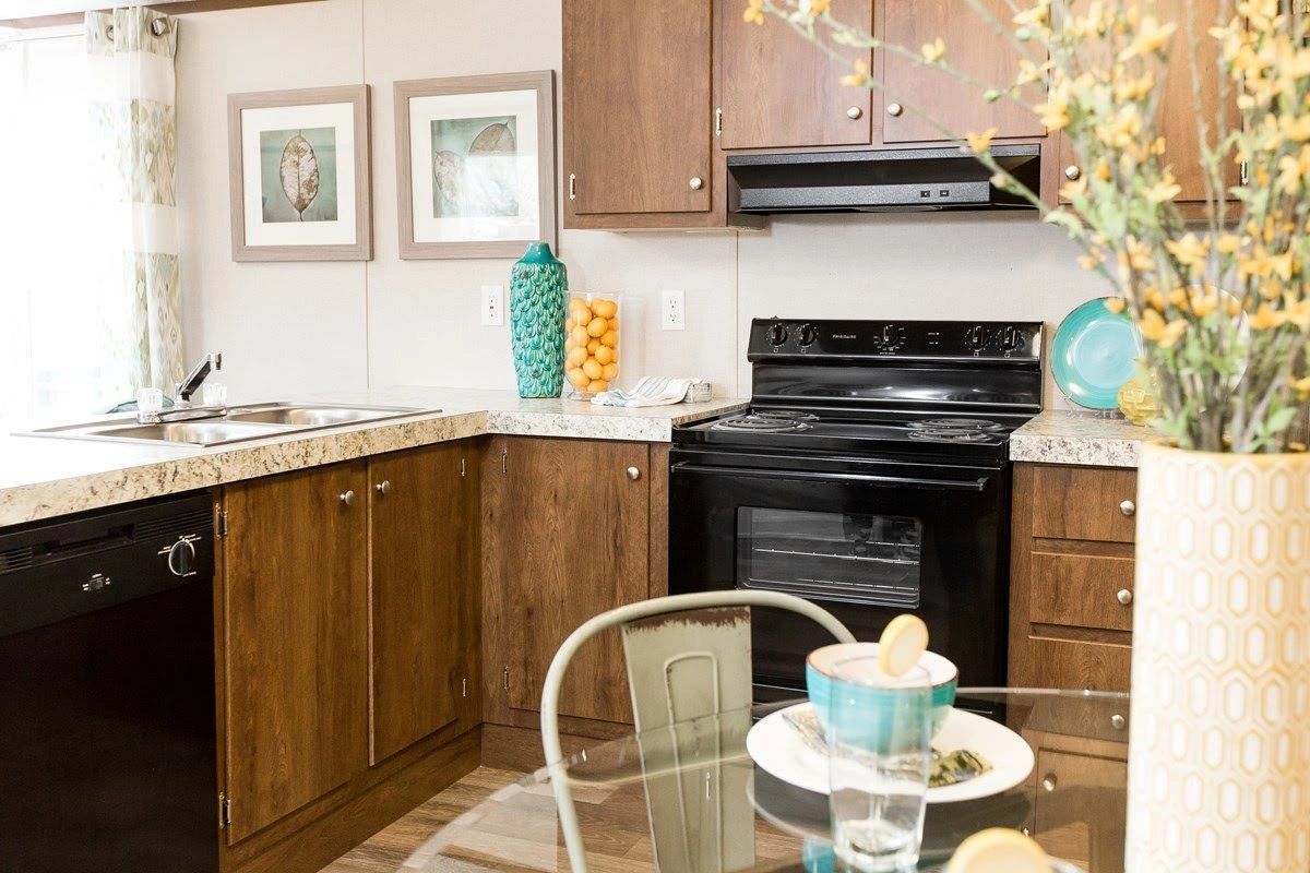 A kitchen with a stove , dishwasher , table and chairs.