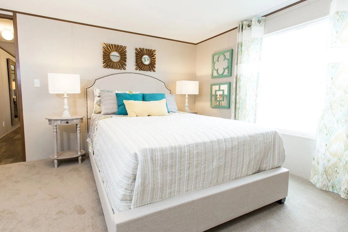 A bedroom with a large bed , lamps , nightstands and a window.