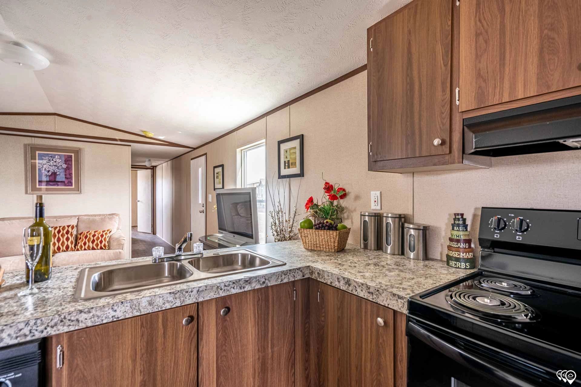 A kitchen in a mobile home with a stove , sink , and refrigerator.