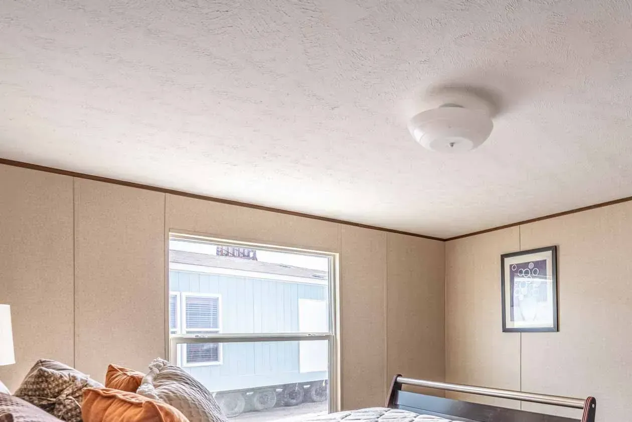 A bedroom with a bed , a window and a ceiling light.