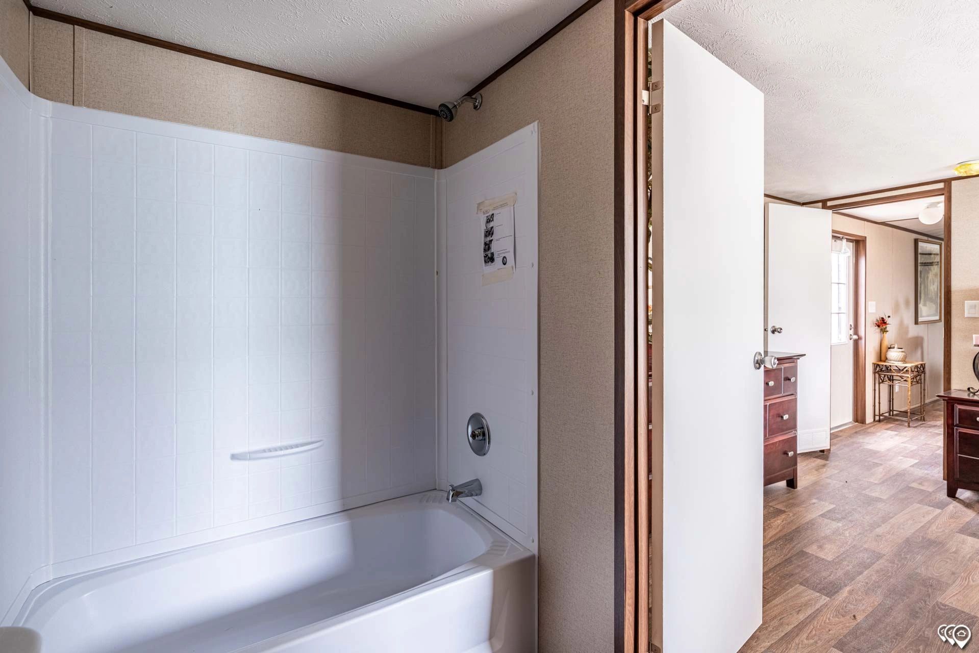 A bathroom in a mobile home with a bathtub and shower.