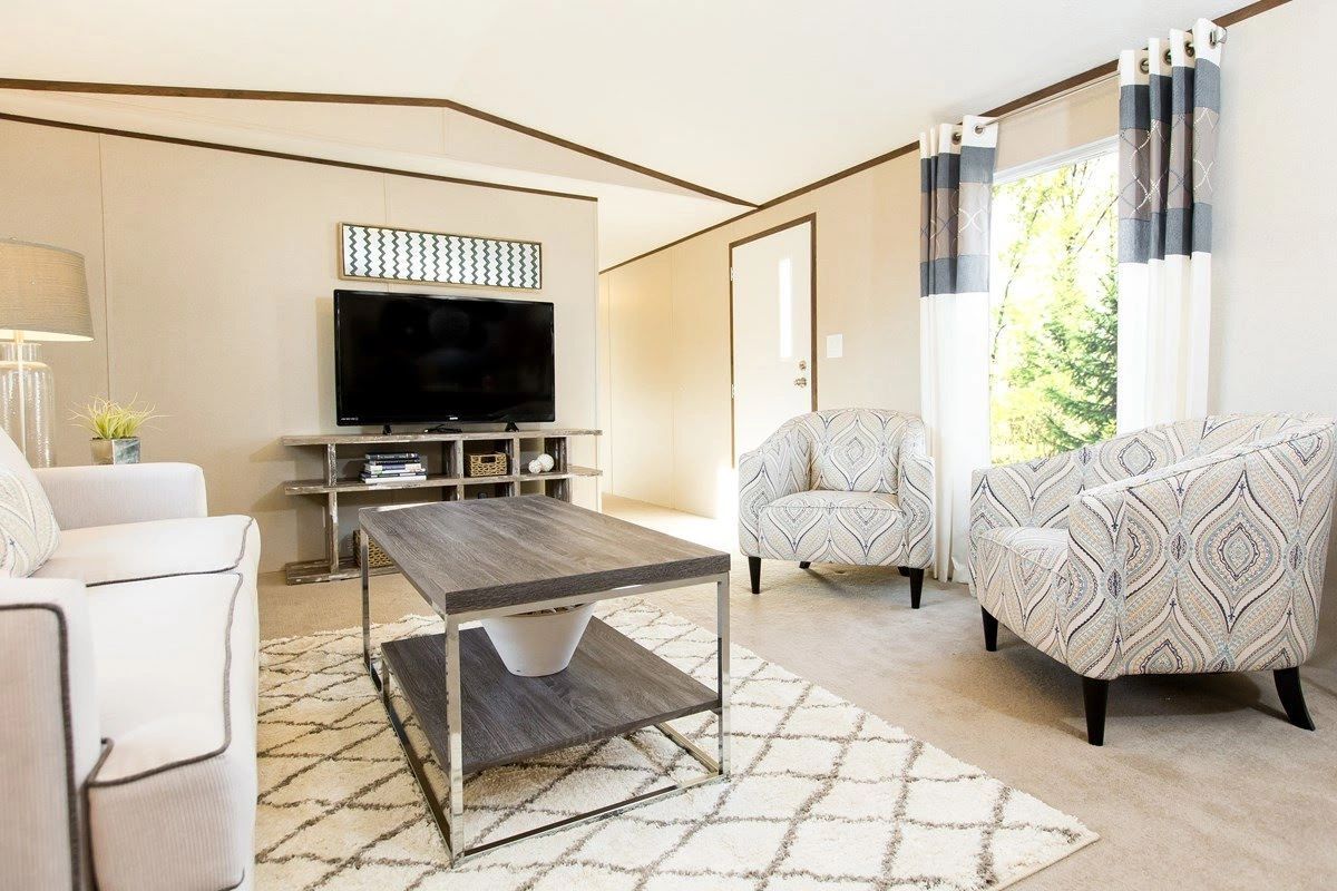 A living room with a couch , chairs , coffee table and television.