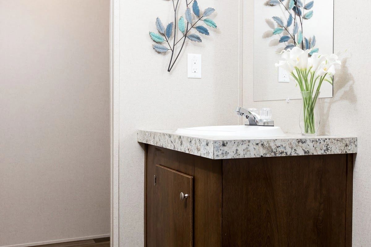 A bathroom with a sink , mirror and vase of flowers.