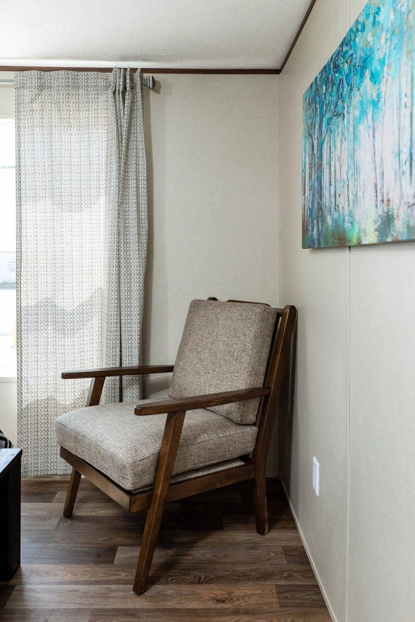 A chair is sitting in a corner of a room next to a window.