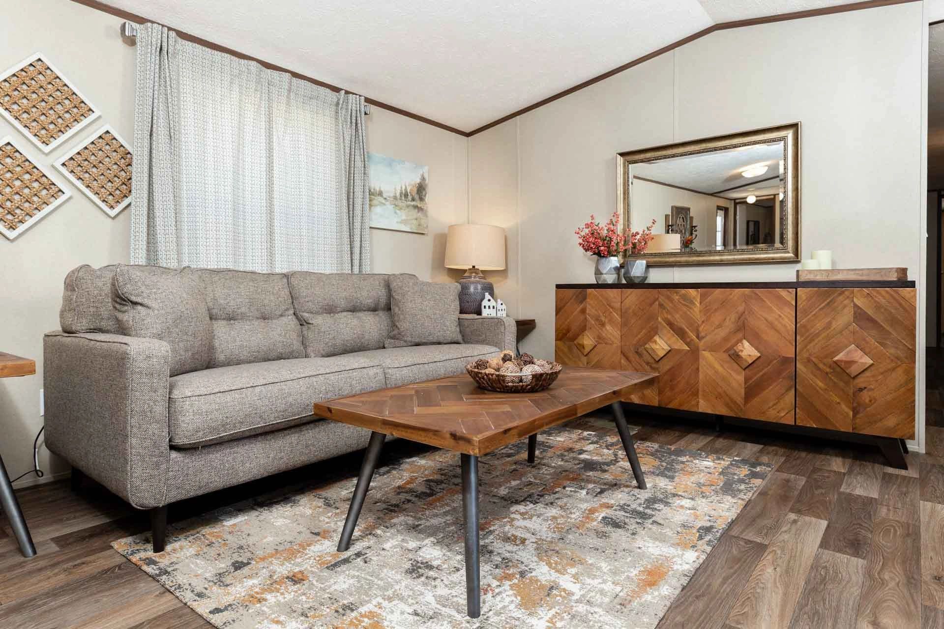 A living room with a couch , coffee table , and mirror.