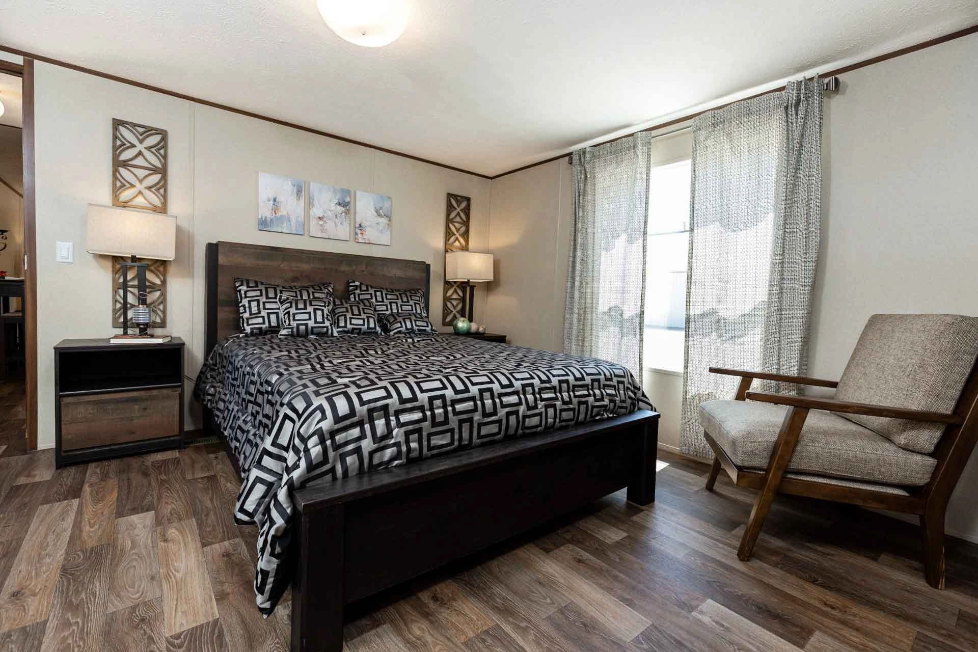 A bedroom with a large bed , chair and nightstand.