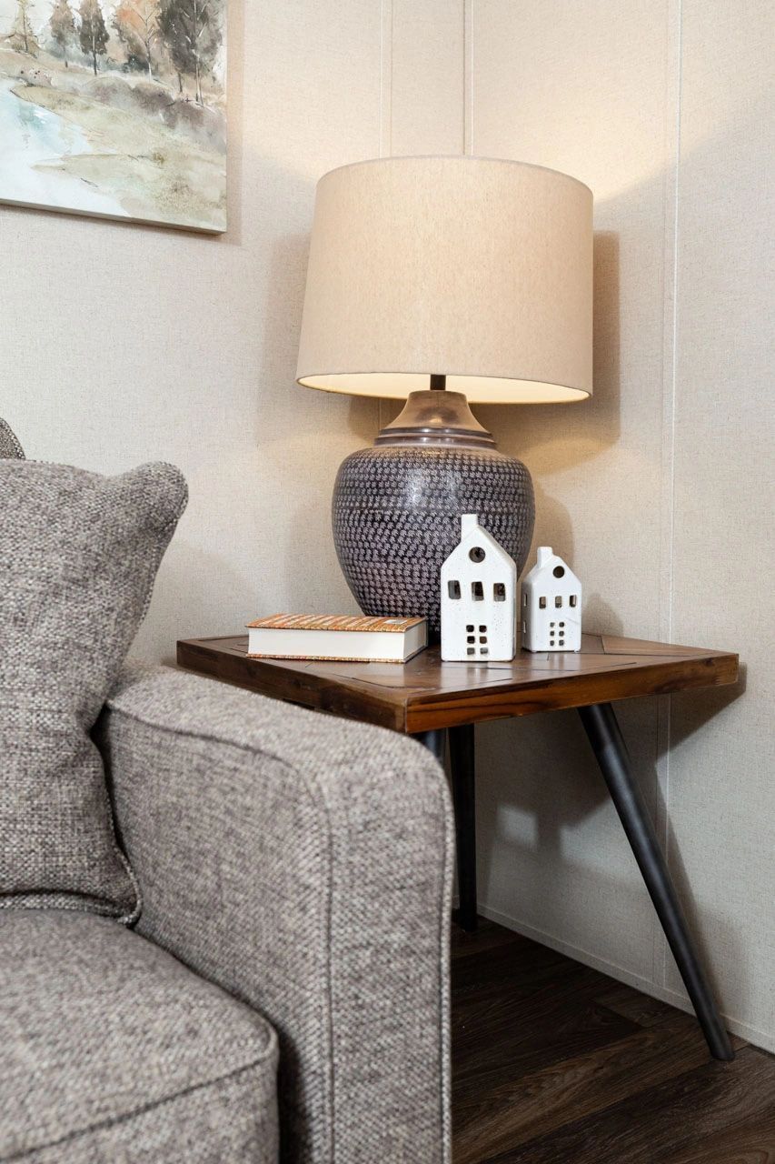A lamp is sitting on a wooden table next to a couch.