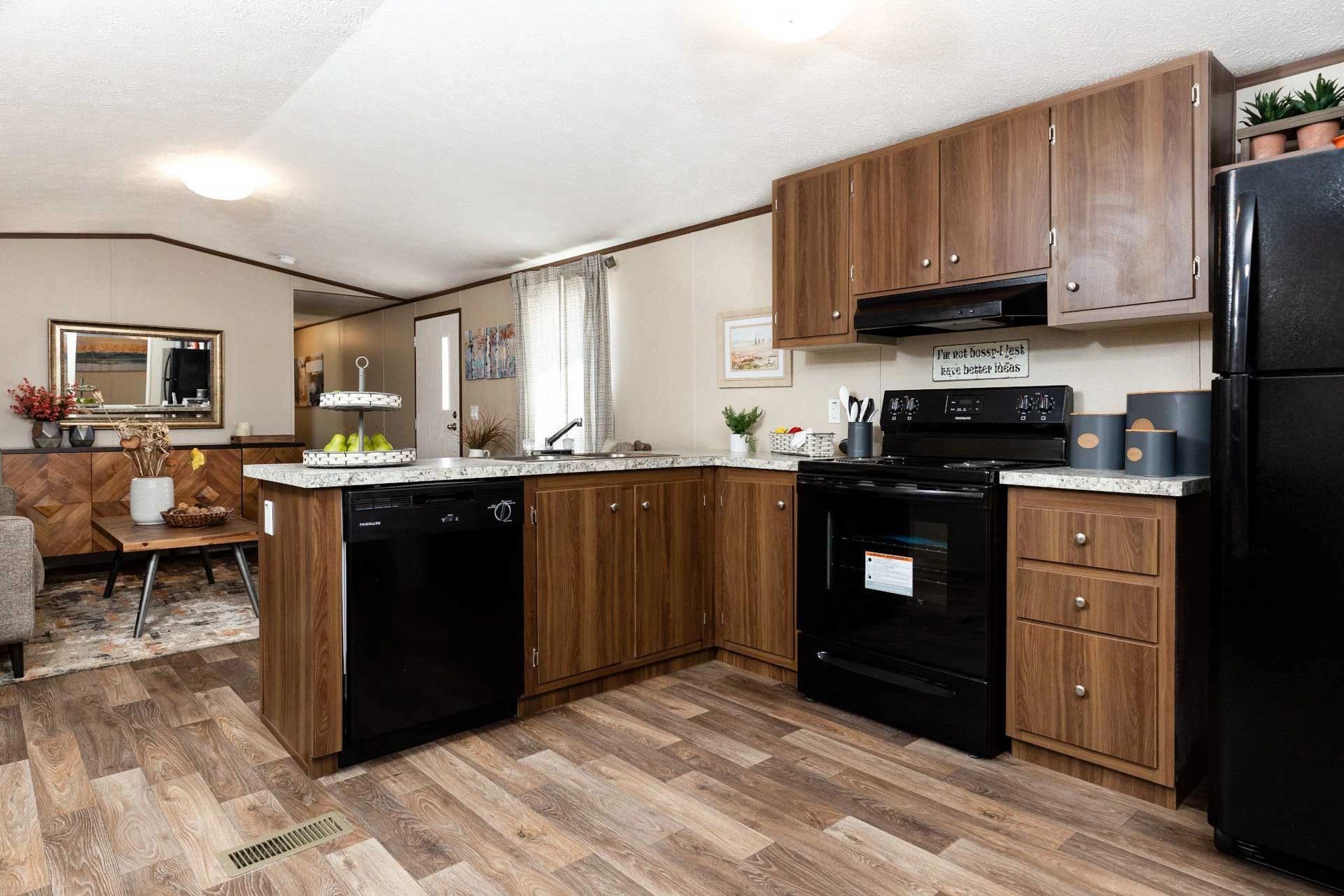 A kitchen in a mobile home with wooden cabinets and black appliances.