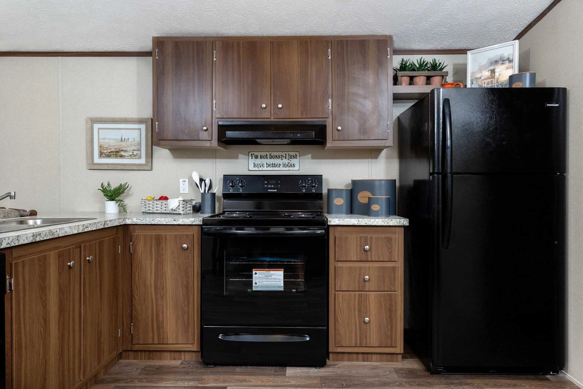 A kitchen with a black refrigerator , stove , and sink.