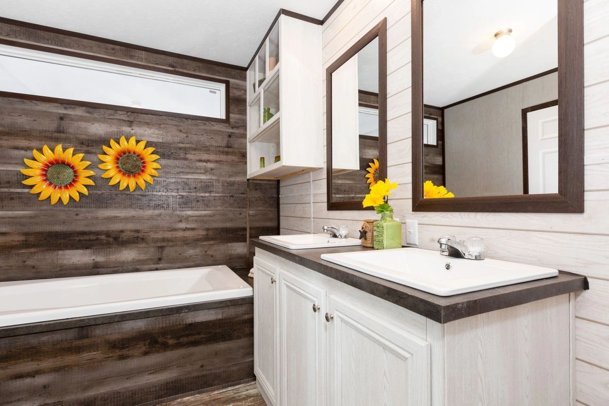 A bathroom with two sinks , a tub and two mirrors.