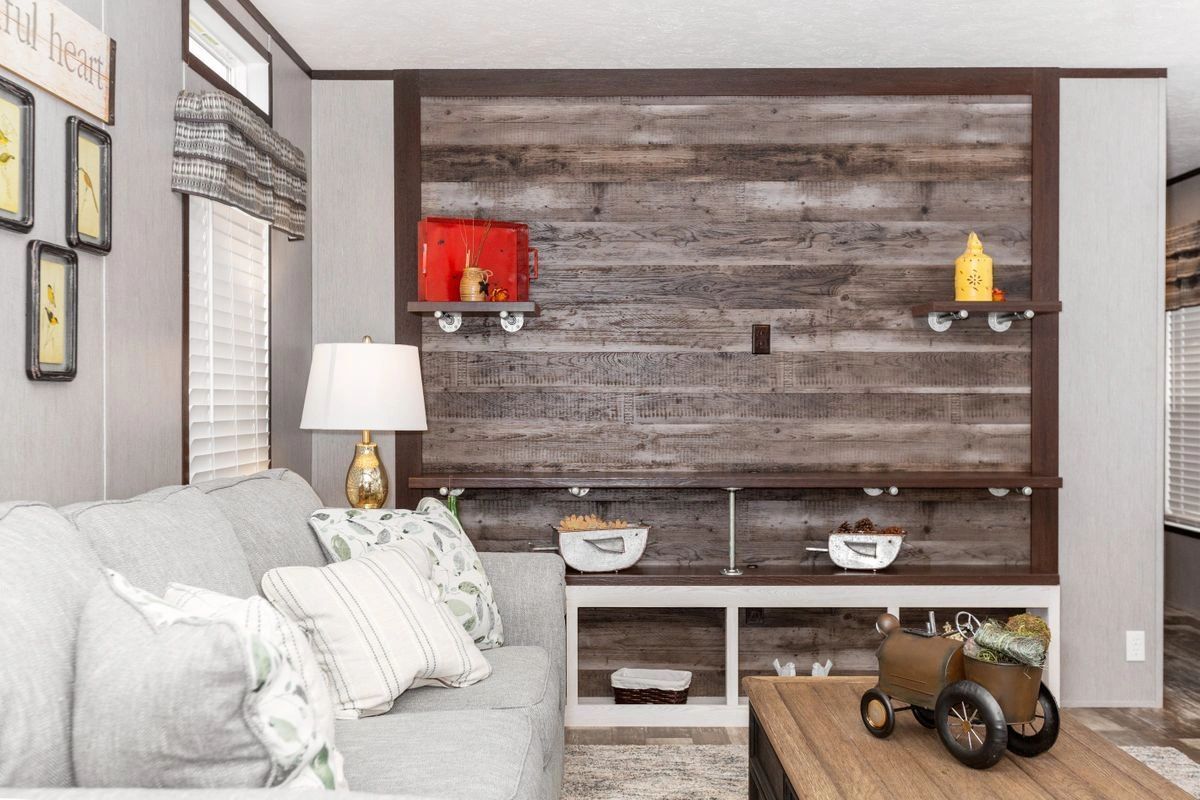 A living room with a couch , table , lamp and wooden wall.