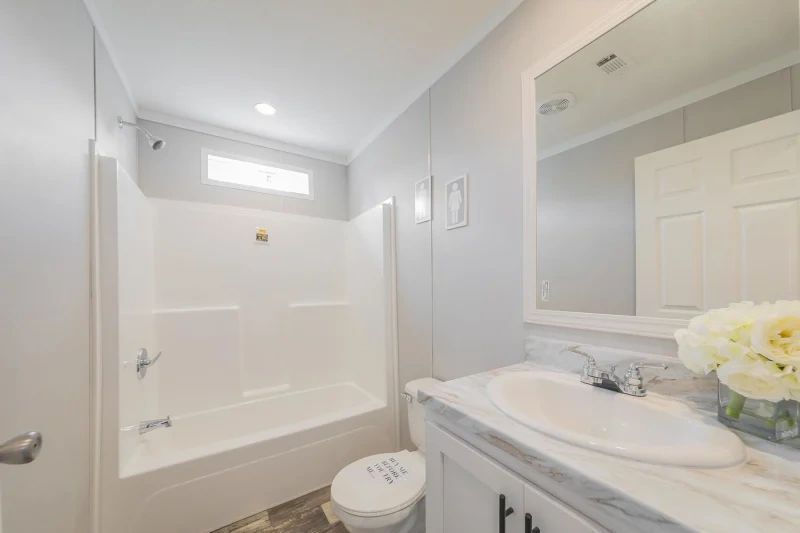 A bathroom with a sink , toilet , shower and mirror.