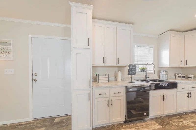 A kitchen with white cabinets , a sink , and a dishwasher.