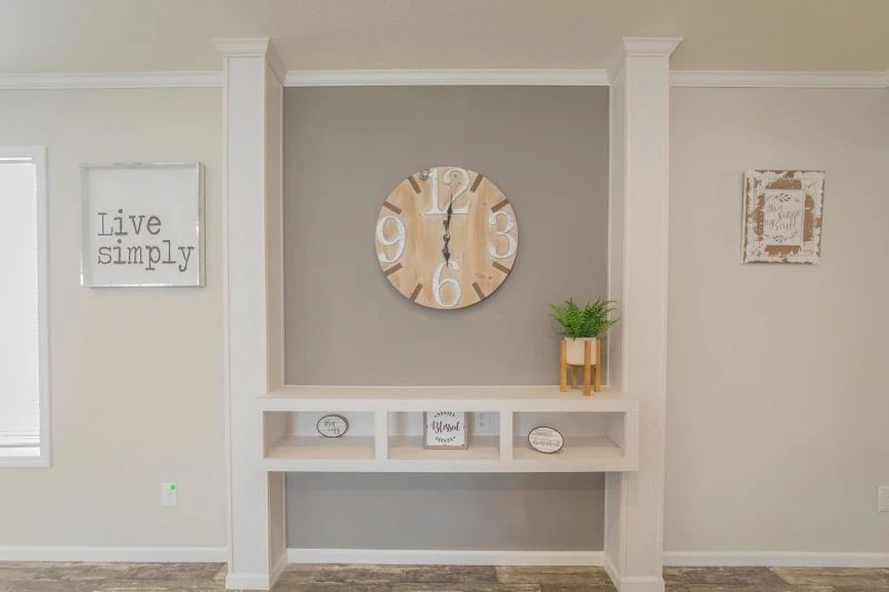 A living room with a clock on the wall and a shelf.