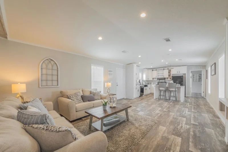 A living room with two couches , a coffee table , and a kitchen.
