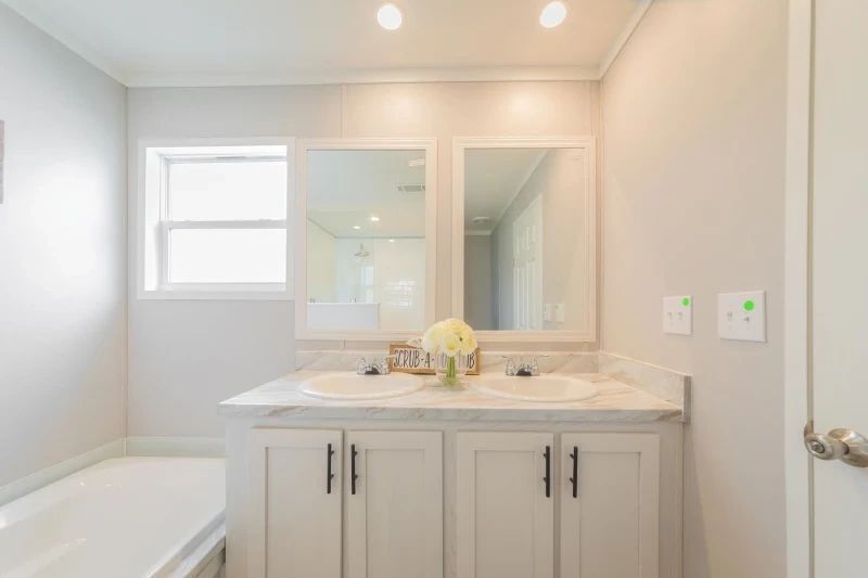 A bathroom with two sinks , a tub and a mirror.