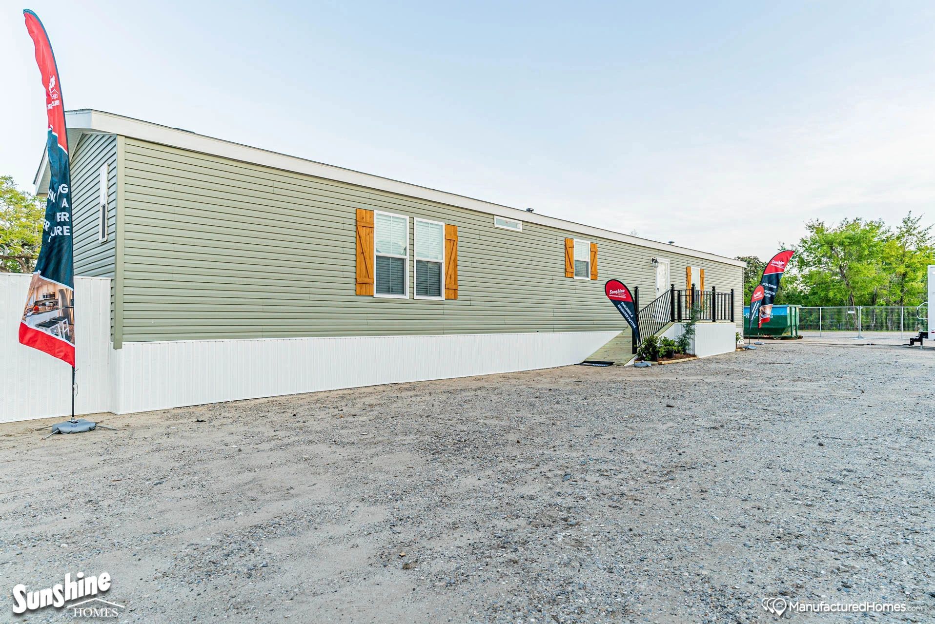 A mobile home is sitting on top of a gravel lot.