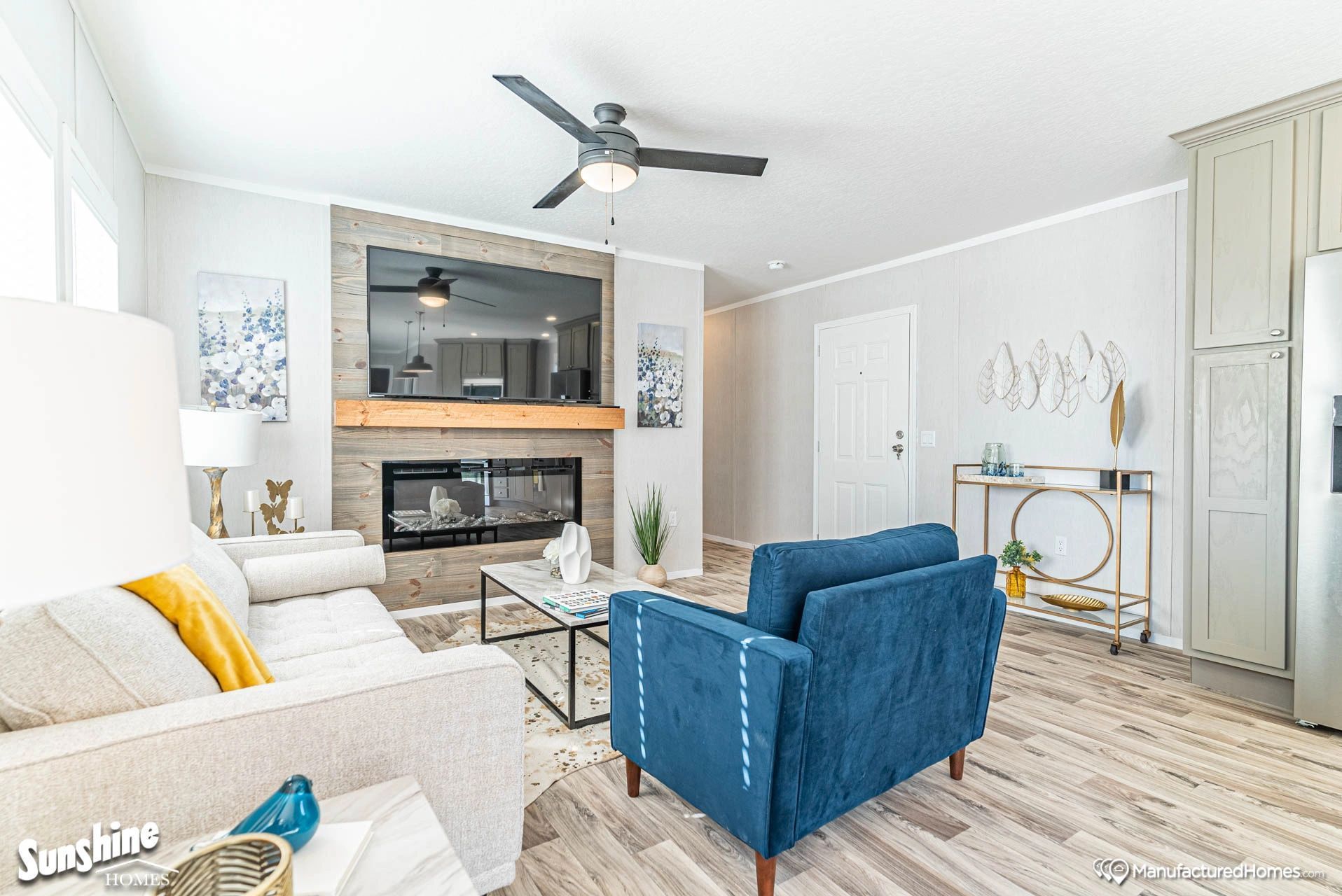 A living room with a couch , chair , coffee table , fireplace and ceiling fan.