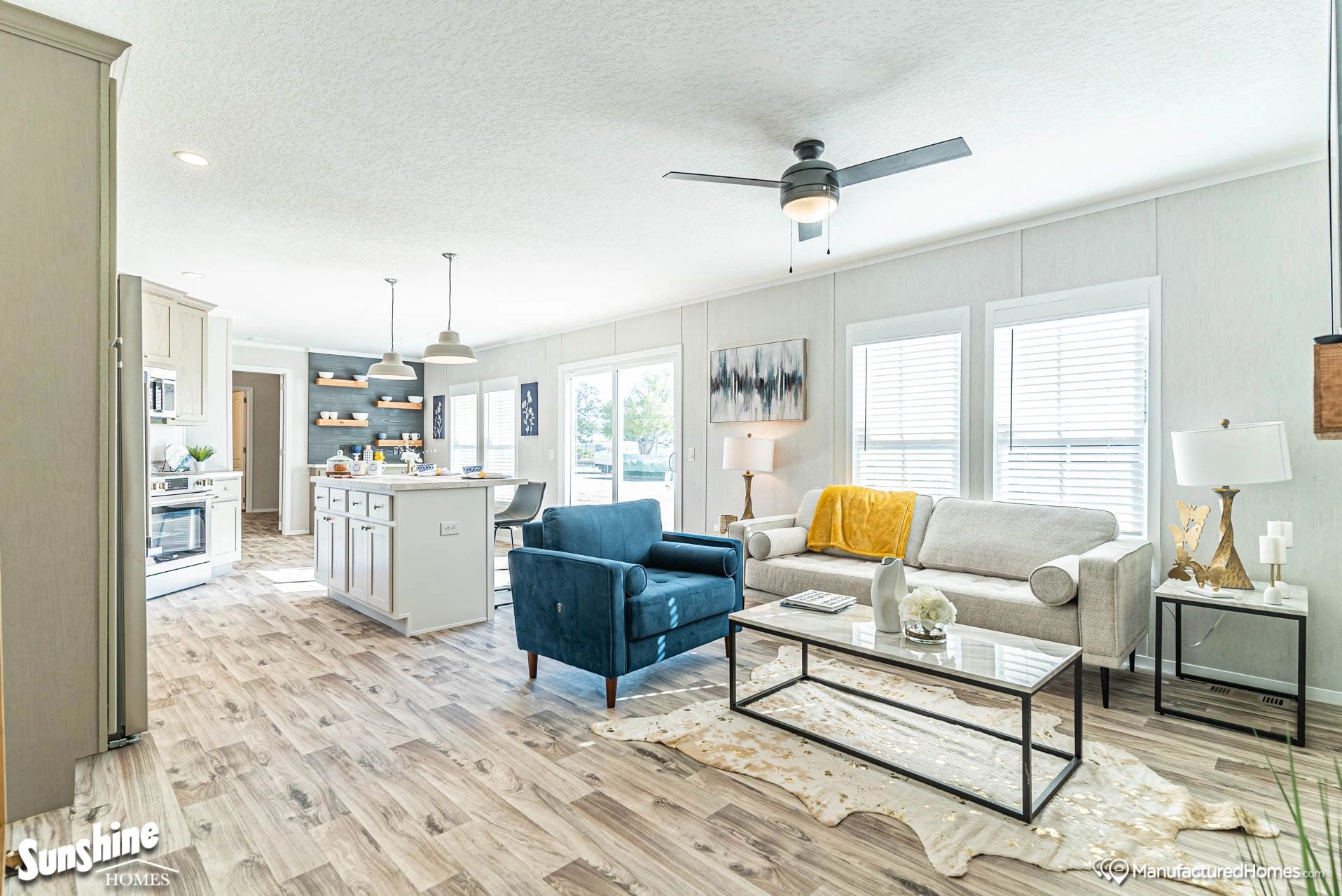 A living room with a couch , chair , coffee table and ceiling fan.