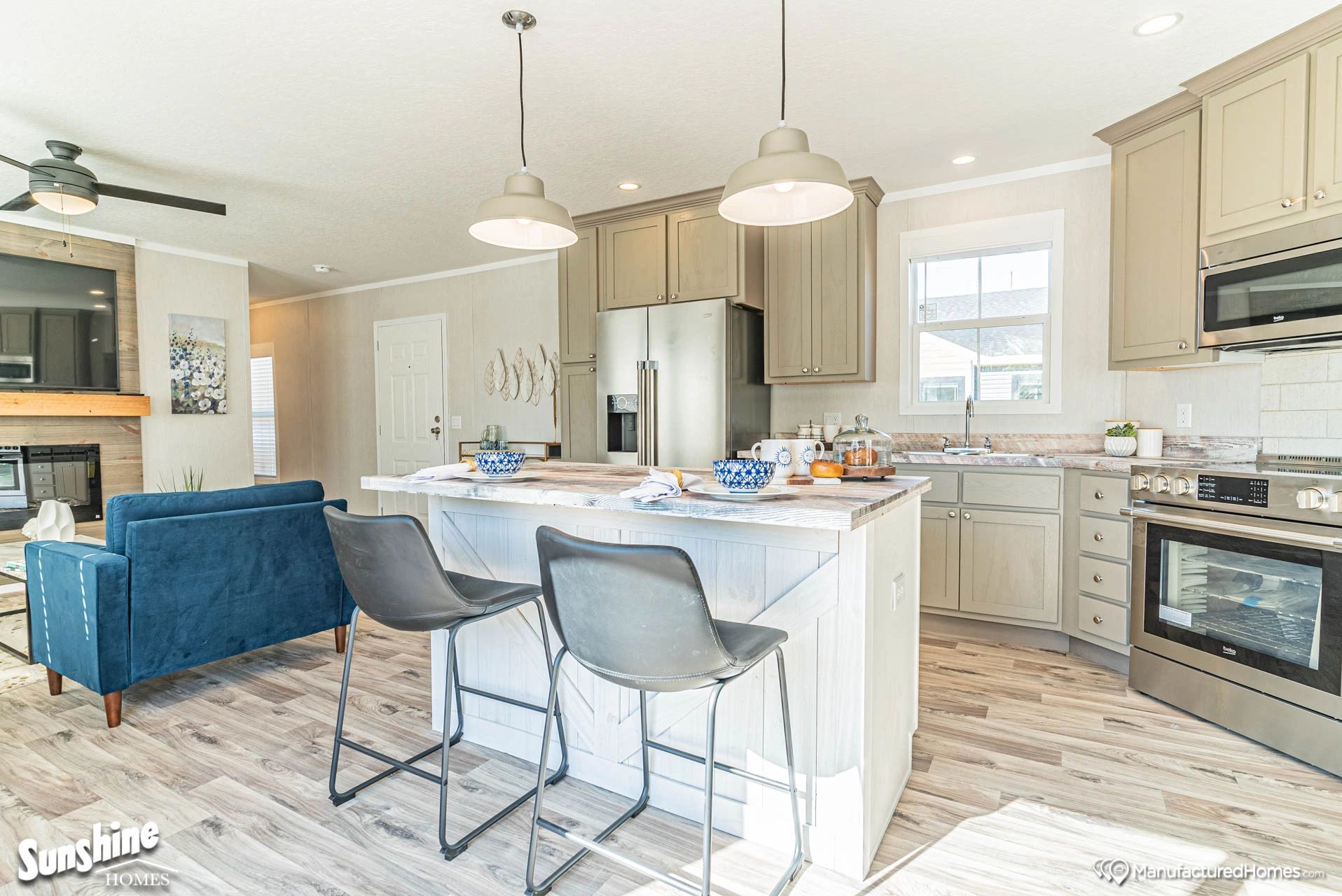 A kitchen with a large island and stools in a mobile home.