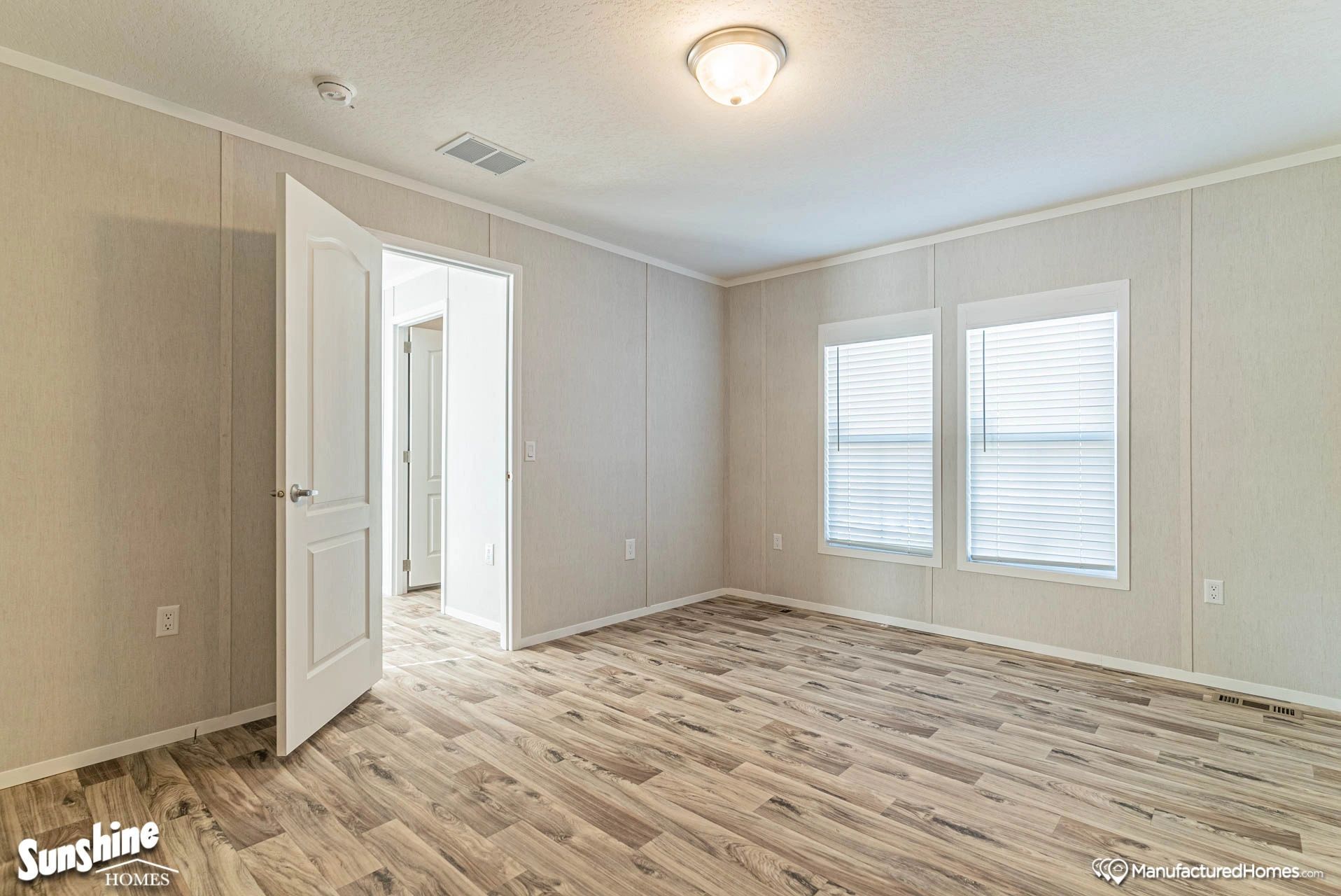A large empty room with hardwood floors and two windows.