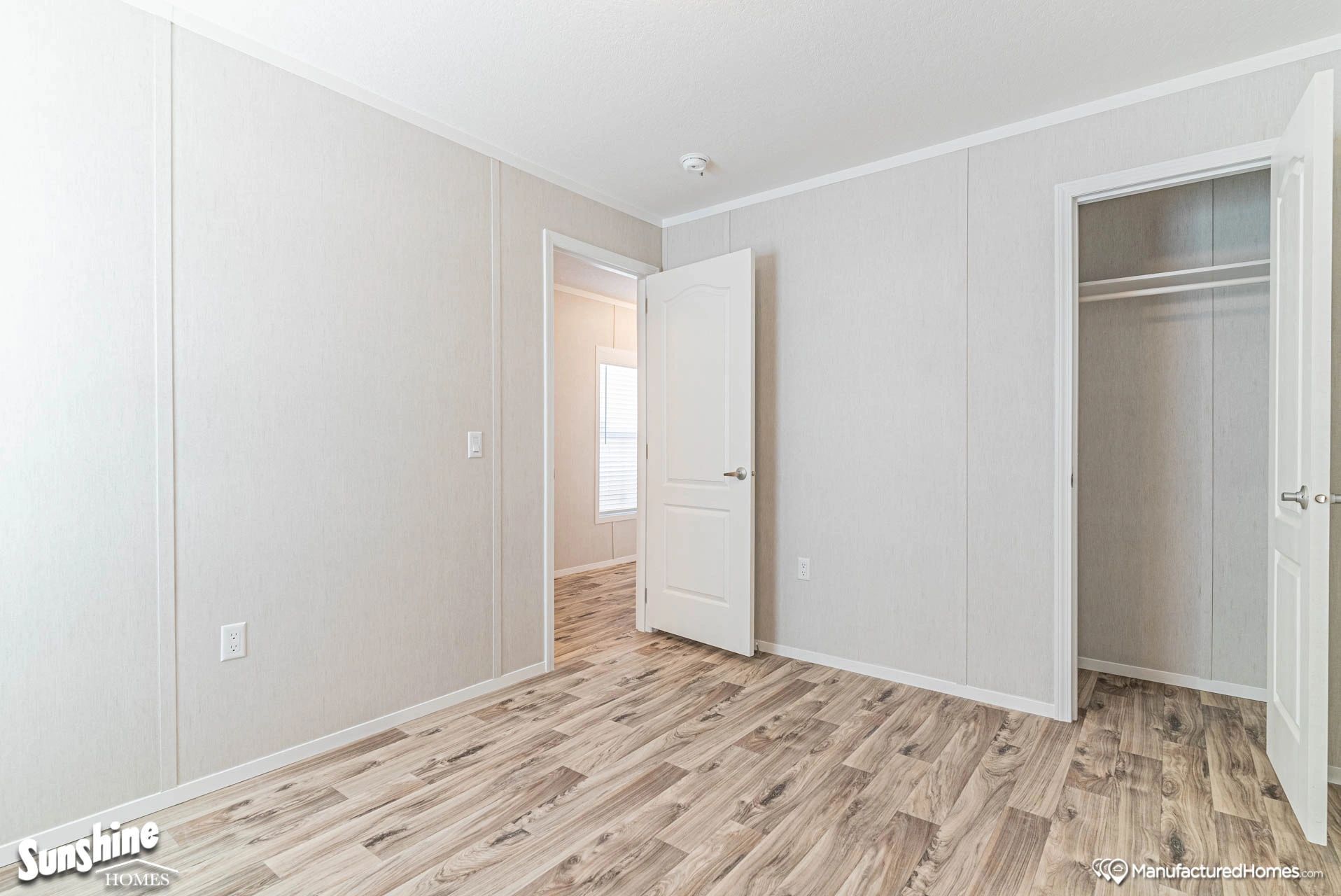 An empty bedroom with hardwood floors and white walls.