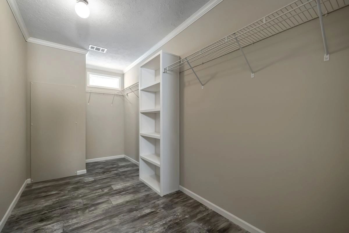 An empty walk in closet with a shelf and a window.