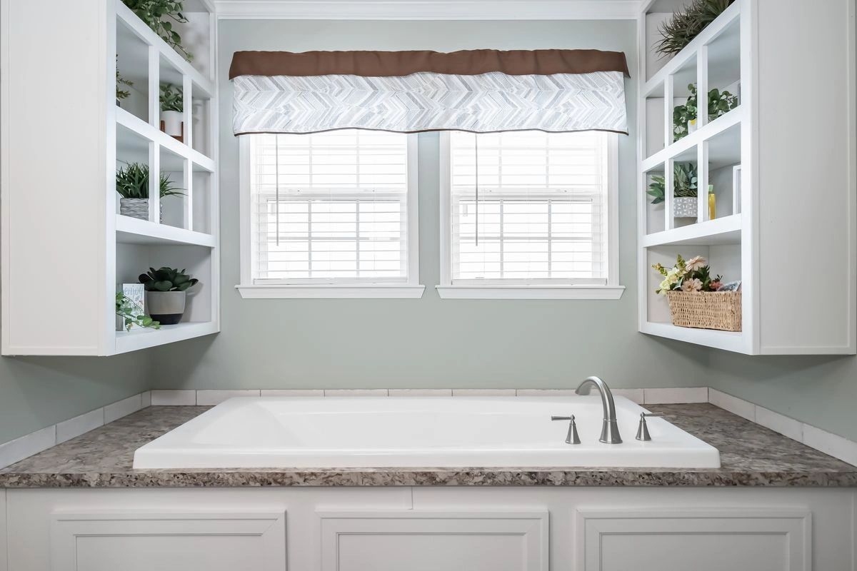 A bathroom with a bathtub and two windows.