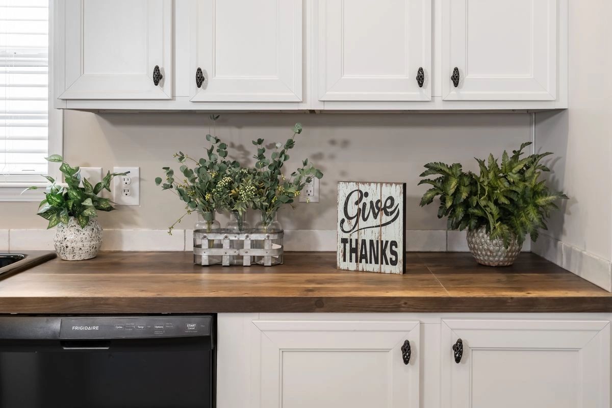 A kitchen with white cabinets and a wooden counter top.