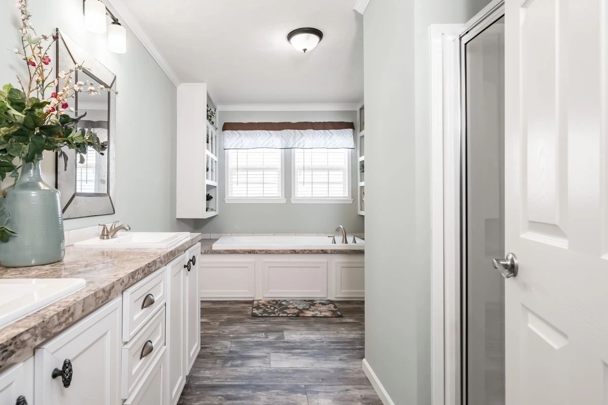 A bathroom with two sinks , a tub and a mirror.