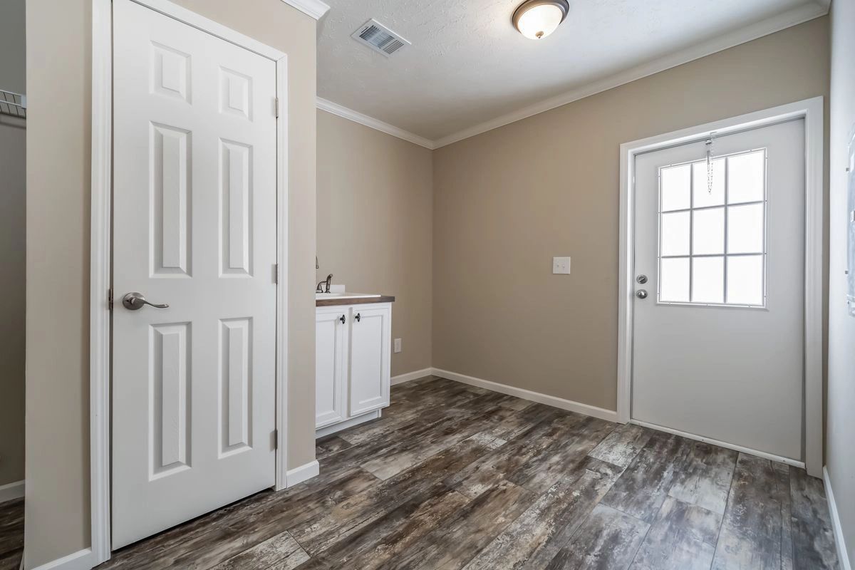 A laundry room with hardwood floors and white doors.
