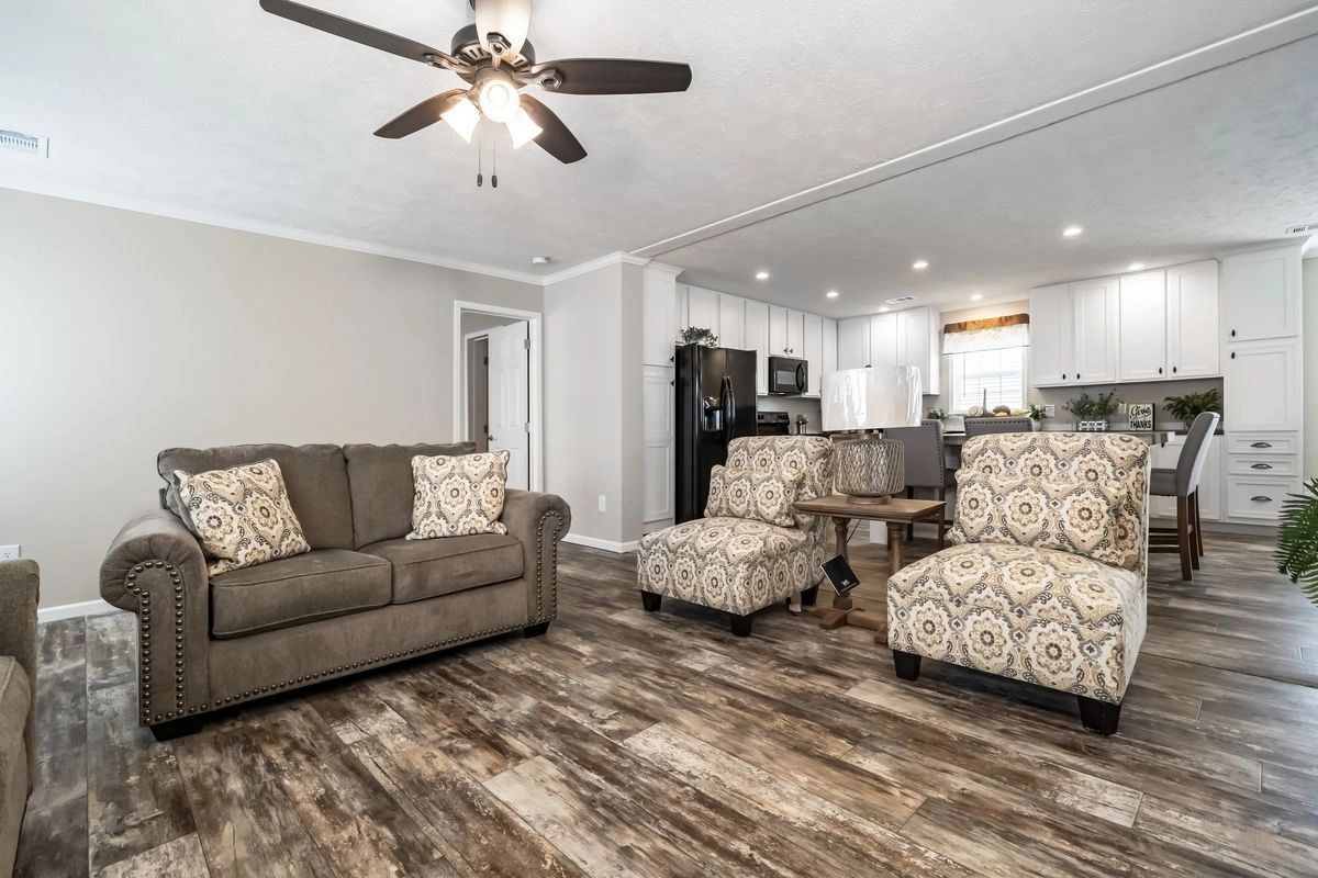 A living room with a couch , chairs and a ceiling fan.