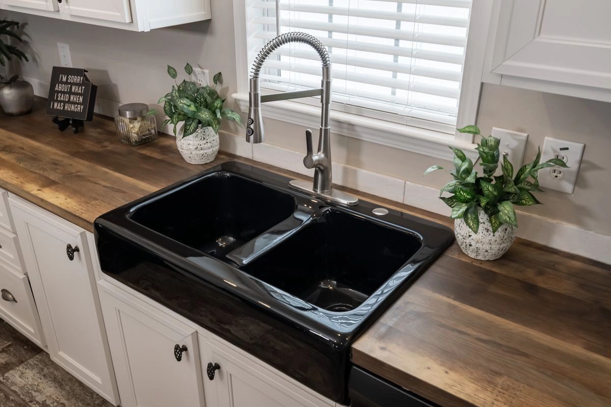 A kitchen with a black sink and a wooden counter top.