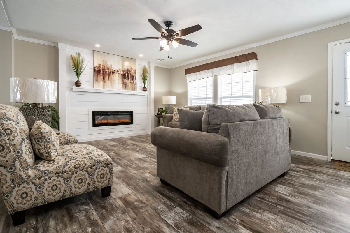 A living room with a couch , chair , fireplace and ceiling fan.