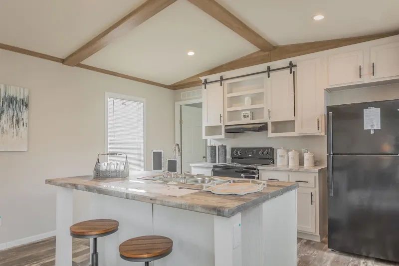 A kitchen in a mobile home with a large island and stools.