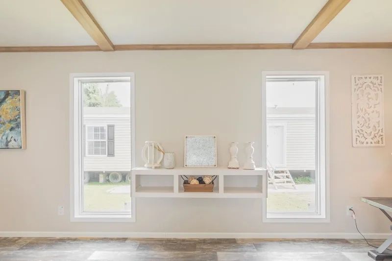 A living room with two windows and a shelf on the wall.