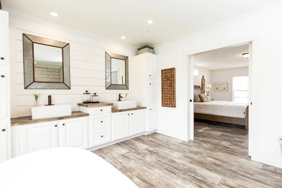 A bathroom with two sinks , two mirrors and a bathtub.