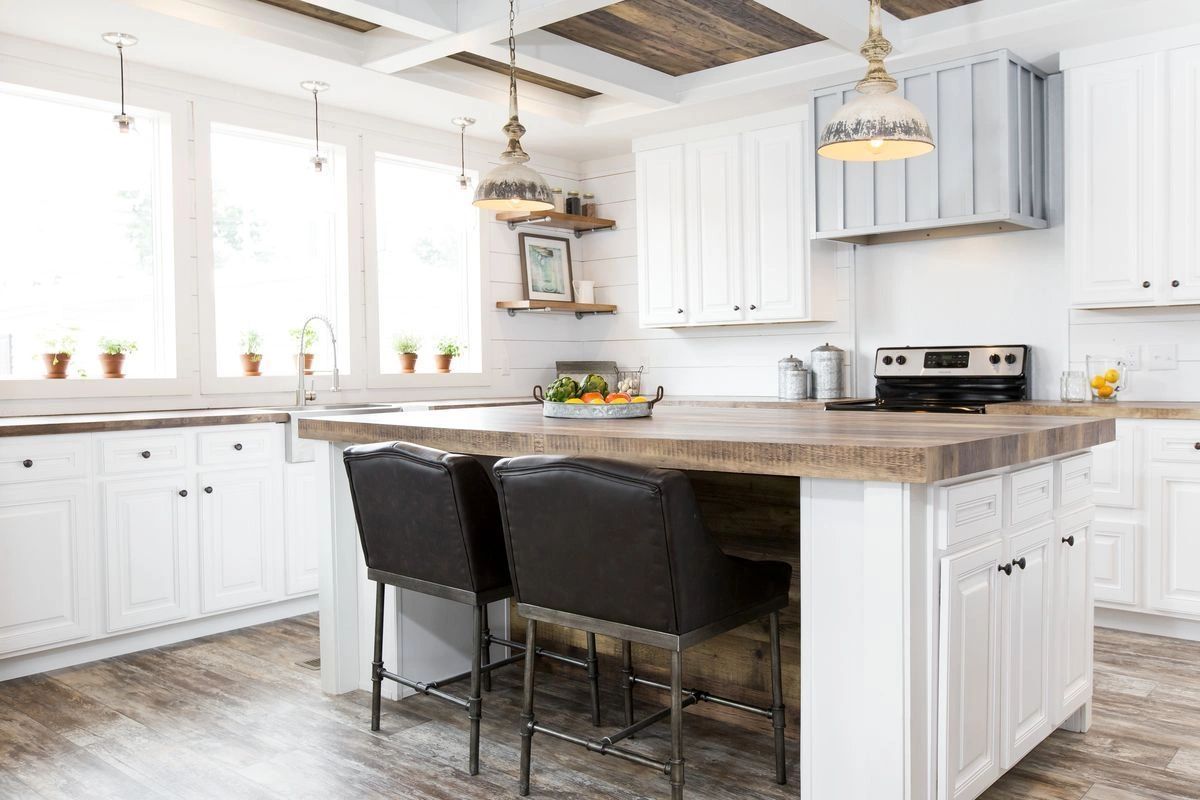 A kitchen with white cabinets , wooden counter tops , and a large island.