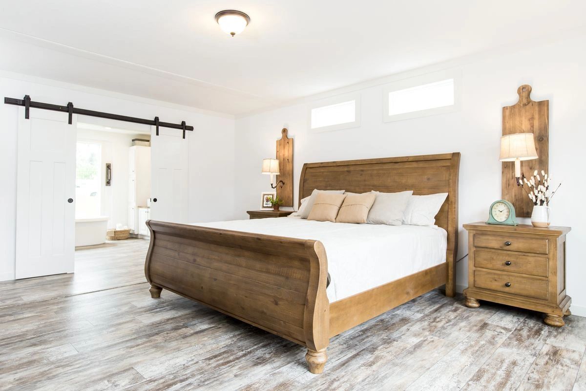 A bedroom with a sleigh bed , nightstand , and dresser.