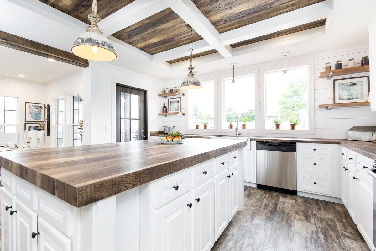 A kitchen with white cabinets and a large island with a wooden counter top.