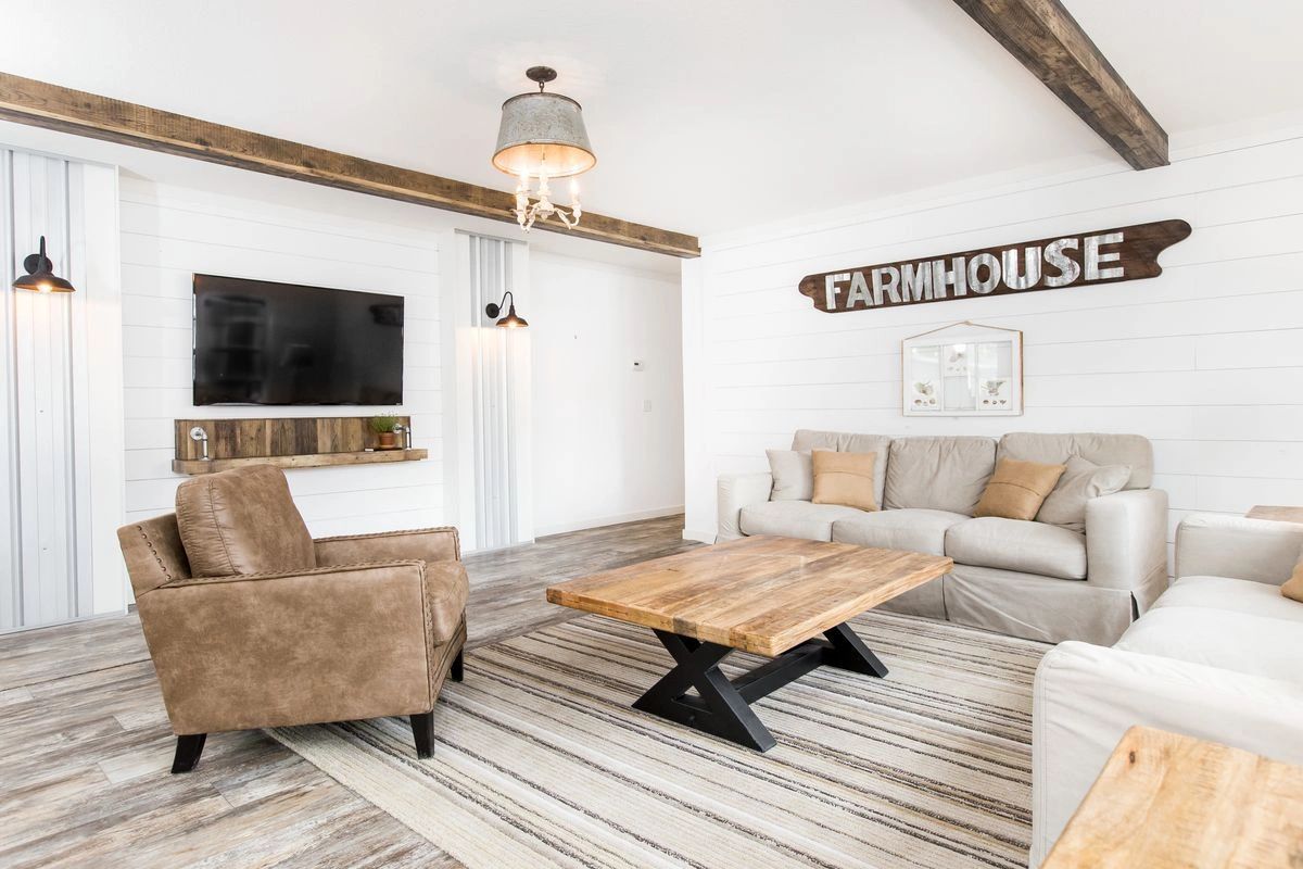 A living room with a couch , chairs , coffee table and television.