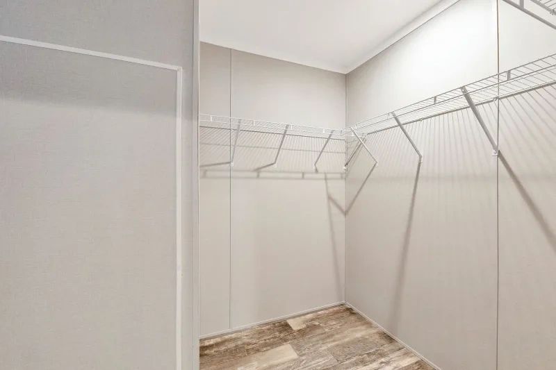 A walk in closet with a lot of shelves and a mirror.
