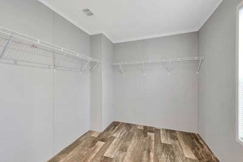 An empty walk in closet with wooden floors and shelves.