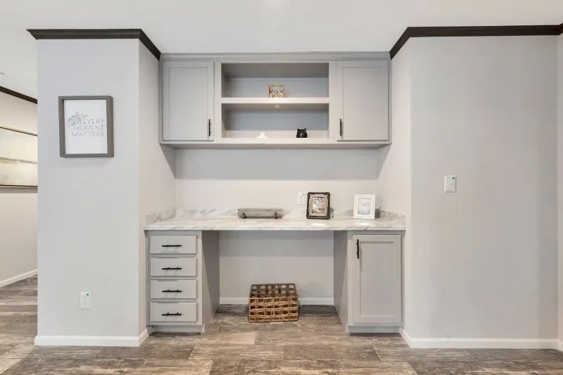 A room with a desk , cabinets , drawers and a picture on the wall.