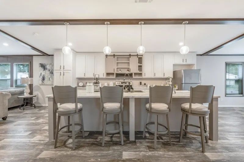 A kitchen with a large island and stools in a house.