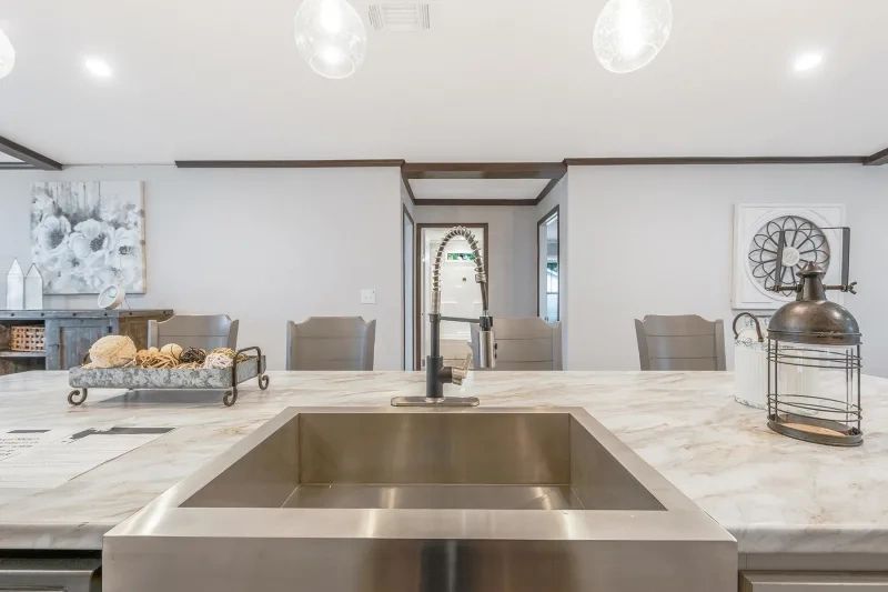A kitchen with a stainless steel sink and a clock on the counter.