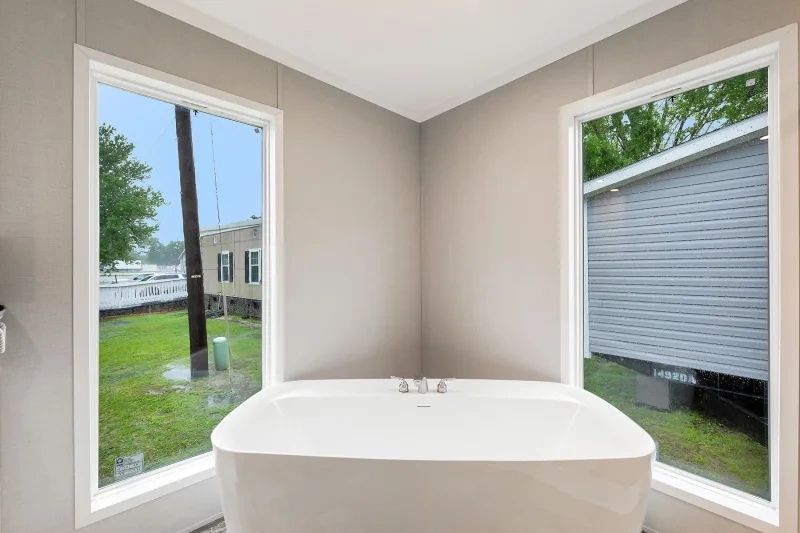 A bathroom with a bathtub and two windows.
