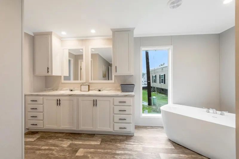 A bathroom with two sinks , a tub and a window.